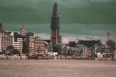 Buildings in city against sky and water in front 