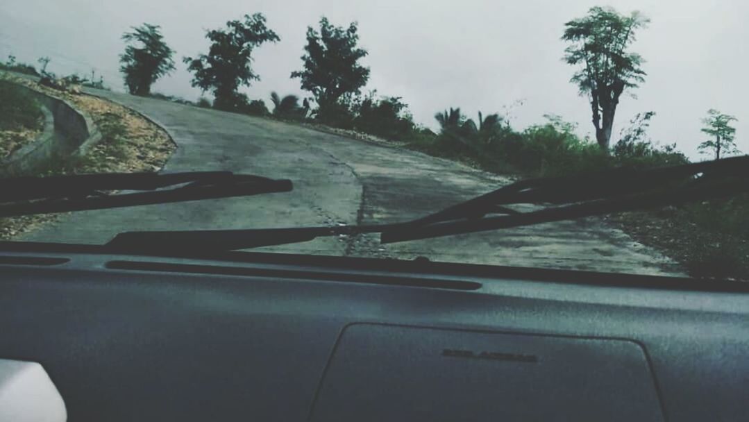 CLOSE-UP OF CAR MOVING ON ROAD AGAINST SKY