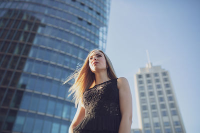 Low angle view of young woman standing outside modern building