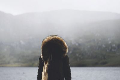 Rear view of man standing in front of lake