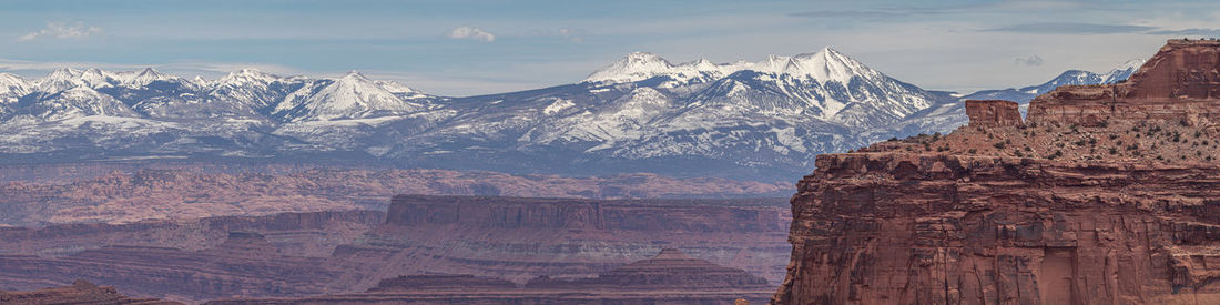 Panoramic view of rocky canyon with snow capped mountains in background