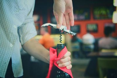 Cropped image of man opening wine bottle at restaurant