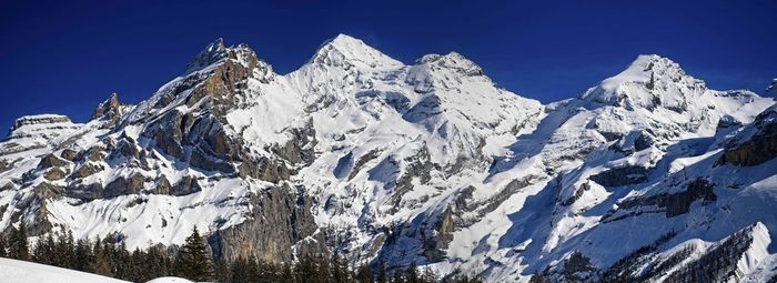 Panoramic view of snowcapped mountains against clear blue sky