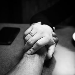 Cropped image of couple holding hands on table in restaurant