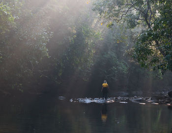 Woman standing by the river side with morning sunlight falling on her