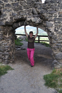 Portrait of smiling woman standing by stone wall