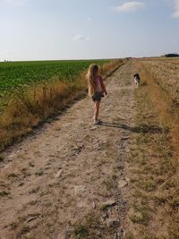 Rear view of man walking on dirt road