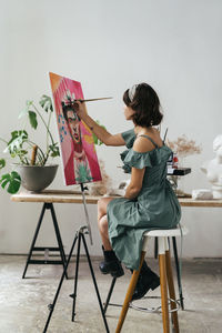 Side view of woman painting on canvas at art studio