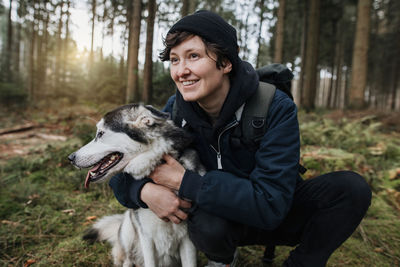 Smiling woman with dog in forest