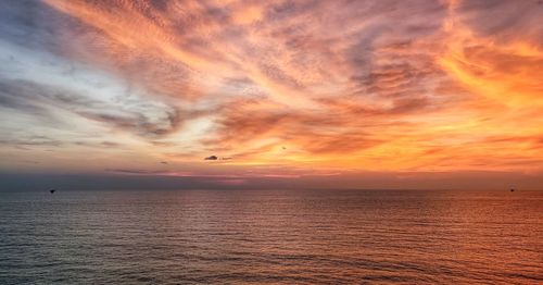 Scenic view of sea against dramatic sky during sunset