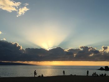 Silhouette people on beach against sky during sunset