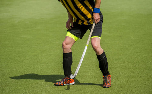 Low section of man playing hockey on grass