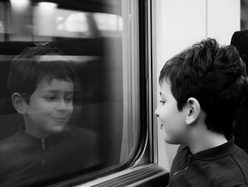 Side view of smiling boy looking through window in train