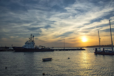 Boats moored at harbor during sunset