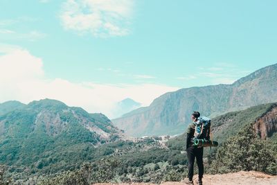 Rear view of man standing on mountain against sky