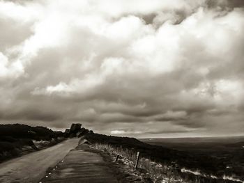 Empty road against cloudy sky