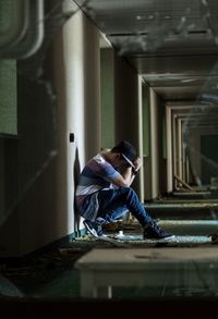 Side view of man sitting on floor