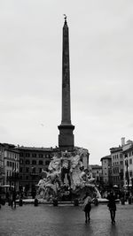 Statue in city against sky