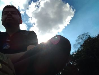 Low angle view of woman sitting against sky