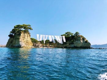 Rock formations in sea against clear blue sky