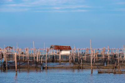 Stilt houses by sea against blue sky