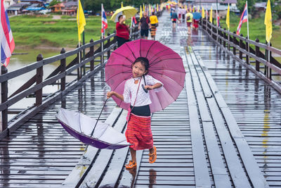 Full length of girl holding umbrella on footbridge