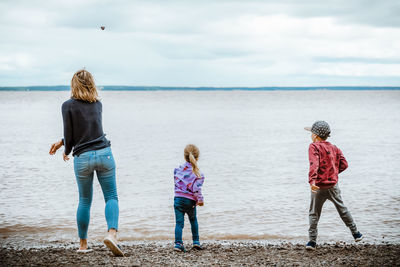 Mother and children throwing rocks in the river