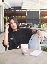 Young woman using mobile phone at table