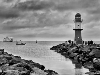 Lighthouse by sea against sky