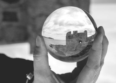 Close-up of hand holding crystal ball with reflection