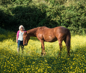 Woman with horse walking on field