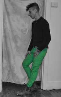 Young man looking away while sitting on wall at home