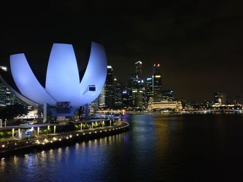 Illuminated city buildings by river at night