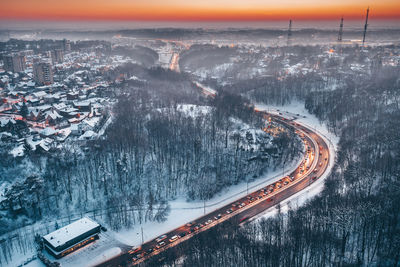 Aerial view of vehicles on road amidst snow covered landscape during sunset