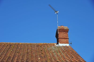 Low angle view of roof and building against clear blue sky