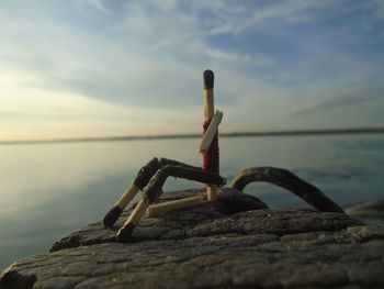 Close-up of wooden post on rock at sea shore against sky