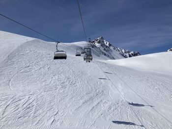 Overhead cable car on snowcapped mountains against sky