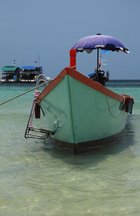 Ship moored on sea against clear blue sky