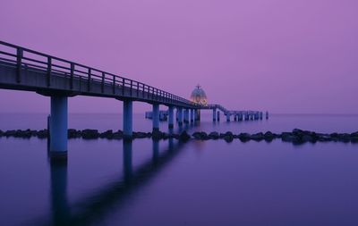 Bridge over sea against clear sky at sunset