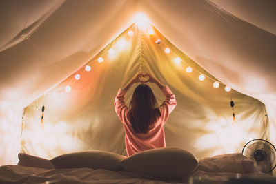 Rear view of woman relaxing on bed