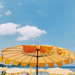 Low angle view of parasols against blue sky