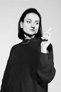 Portrait of young woman standing against white background