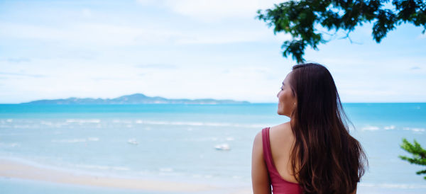 Side view of woman standing at beach against sky