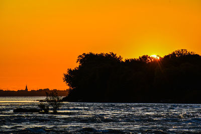 Scenic view of silhouette trees against orange sky