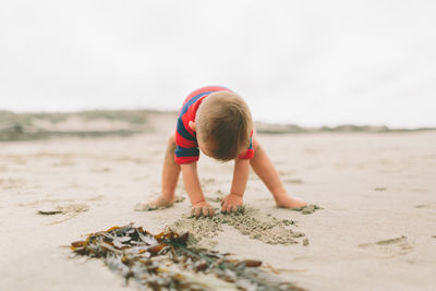 Boy on sand at beach against sky