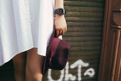 Midsection of woman holding hat on sunny day