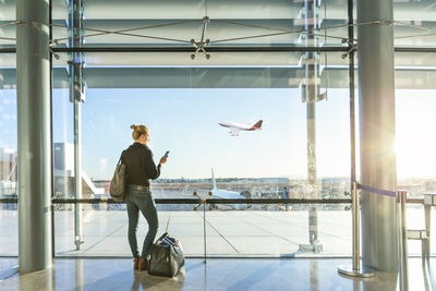 Rear view of man standing by airplane window