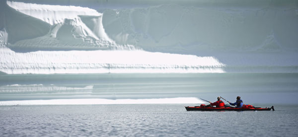 2 men traveling on a sea-kayak though the fjords of eastern greenland