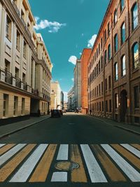 Road amidst buildings in city against sky