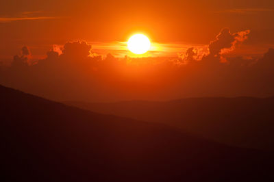 Scenic view of silhouette mountains against romantic sky at sunset